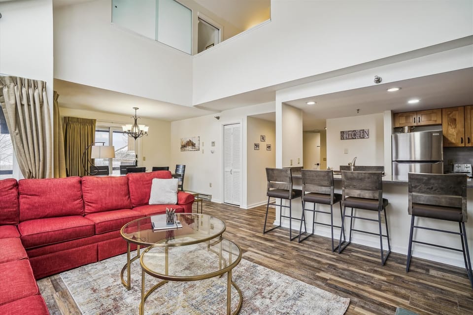 The living room, dining area, and loft-style upper level create an airy mountain retreat.