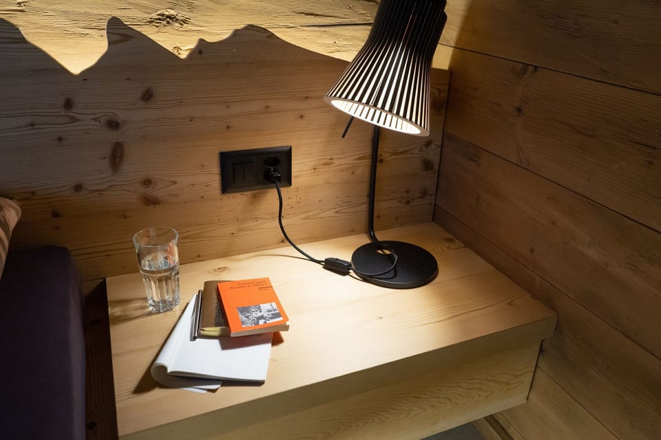 Wooden bedside table with a reading lamp, books and a glass of water