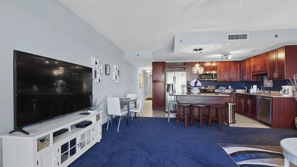 modern open kitchen and living area with blue carpet and stainless steel appliances