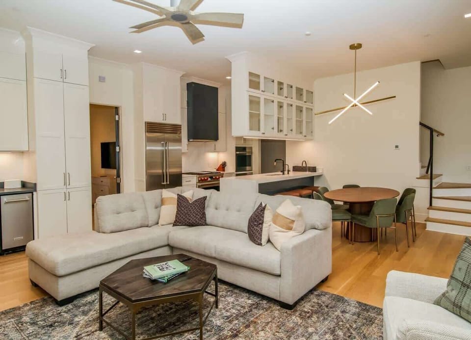 Bright, open-concept living area with plush sectional seating, warm hardwood floors, and seamless flow into the dining space.