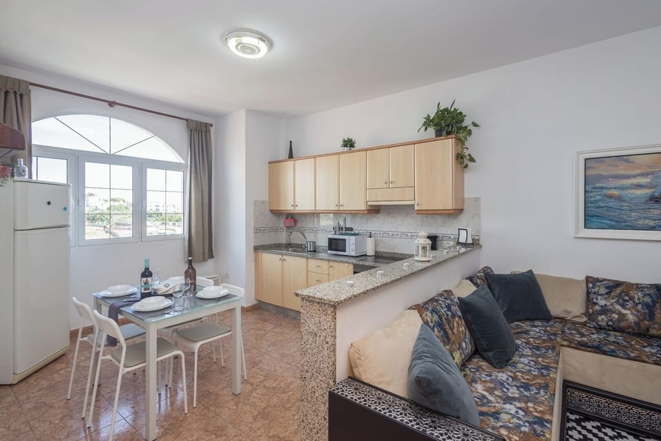 
La cocina de este piso turístico en Agüimes es un espacio moderno y funcional con una distribución abierta que fluye perfectamente hacia el área de comedor y la sala de estar.