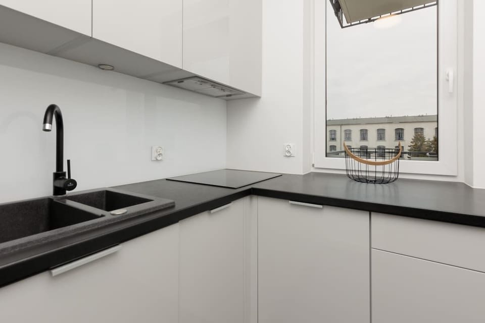 A sleek kitchen with white cabinets, black countertops, and minimalist design, featuring integrated appliances for a clean look.
