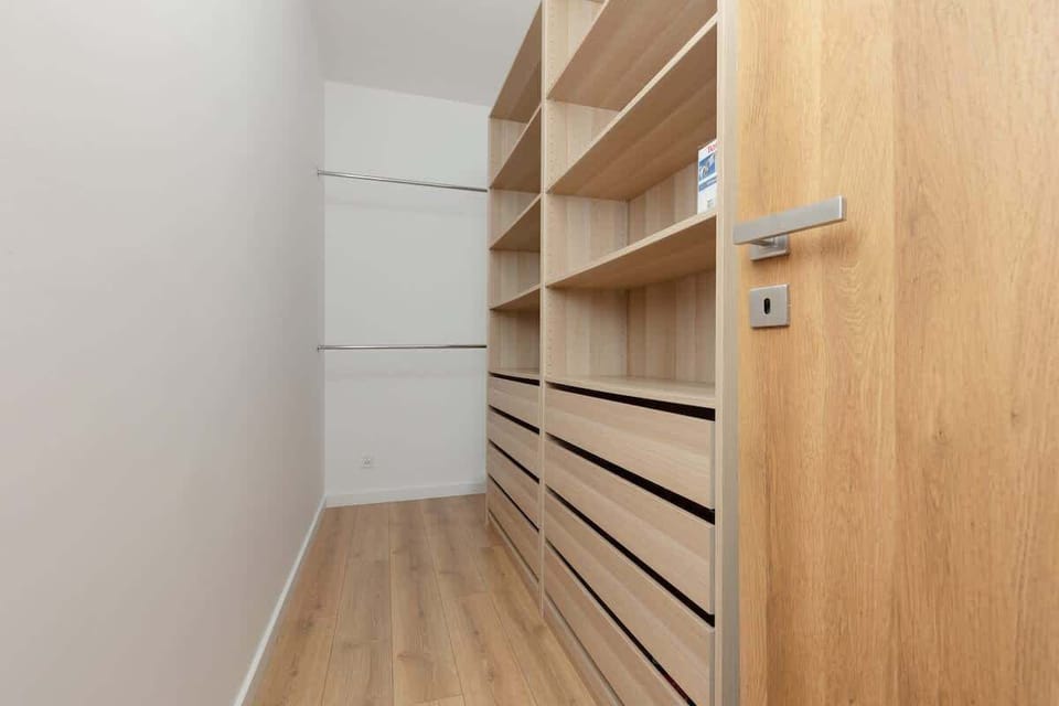 A walk-in closet with wooden shelving, ample storage, and minimalist design, maximizing organization and space.
