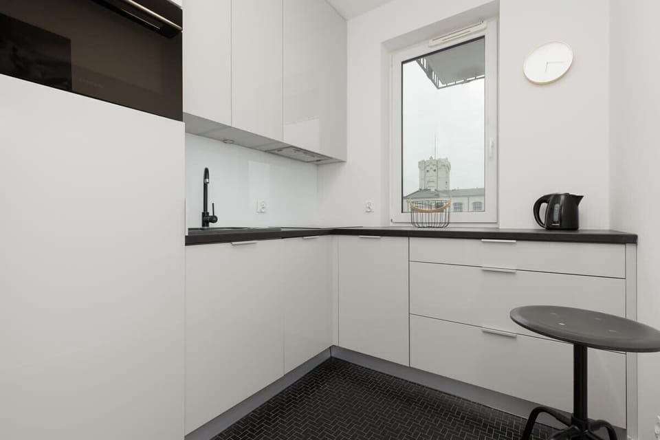 A monochrome kitchen with white cabinets, black countertops, and a minimalist breakfast nook, creating a sleek and functional space.
