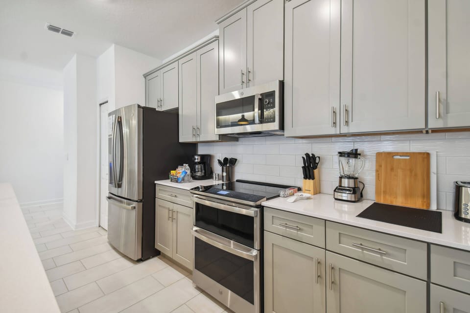 Step into a sleek kitchen featuring soft gray cabinetry and a stylish black refrigerator, perfect for preparing meals. The clean lines and modern appliances create a welcoming atmosphere for culinary adventures.