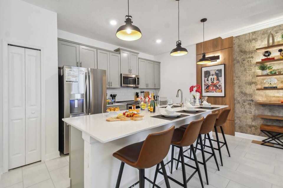 Experience a beautifully designed kitchen featuring sleek grey cabinetry and a striking accent wall, perfect for culinary adventures. The spacious island with stylish bar stools invites casual dining and vibrant conversations.