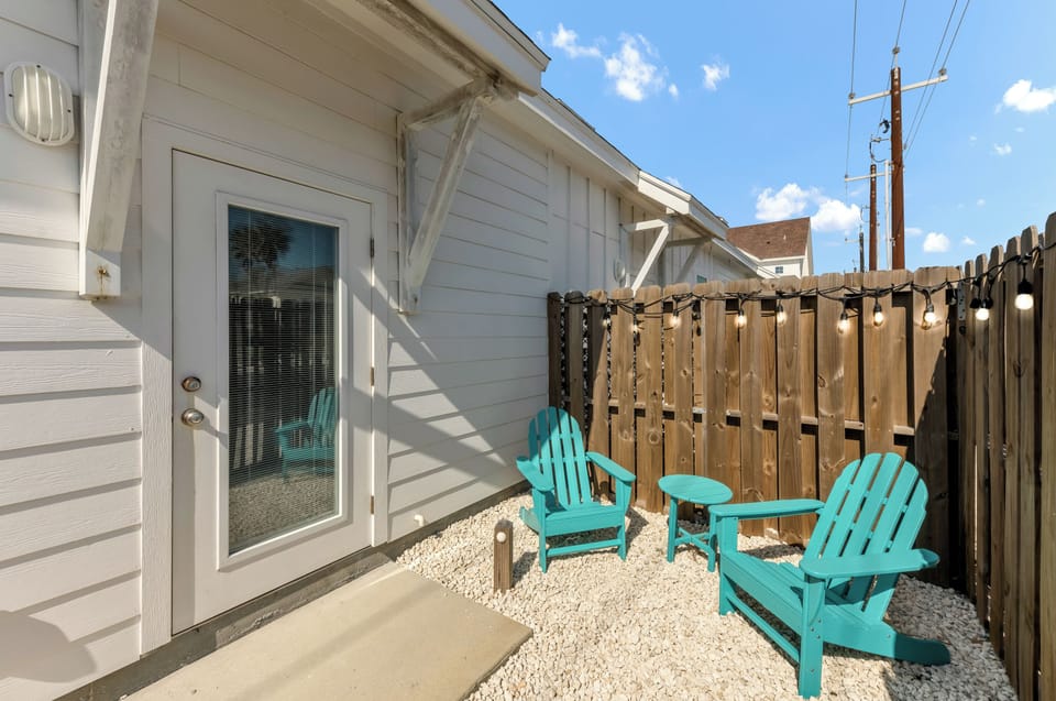 Step into your private patio oasis where turquoise Adirondack chairs await your morning coffee and evening conversations under twinkling lights.