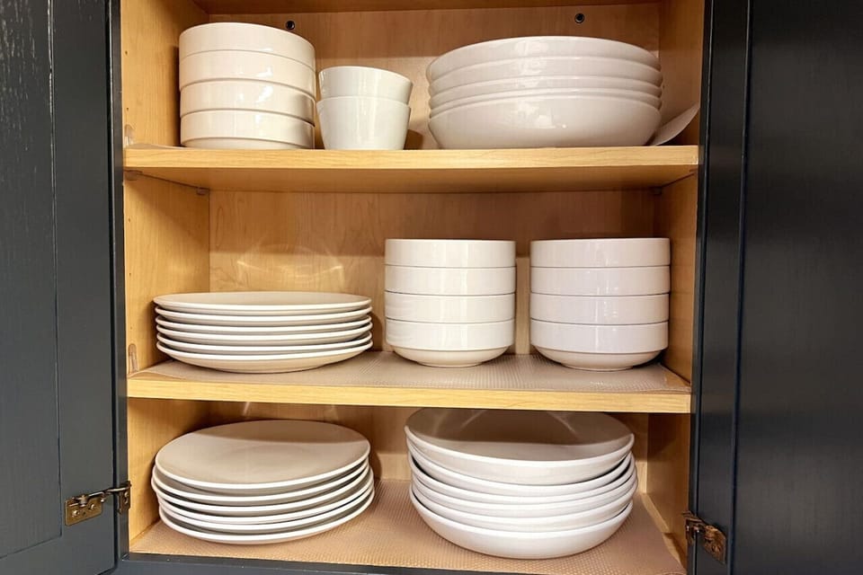 Explore the upper cabinet left of the oven for bowls, versatile `bowl-in-one` dishes, and elegant dinner plates for your dining convenience.