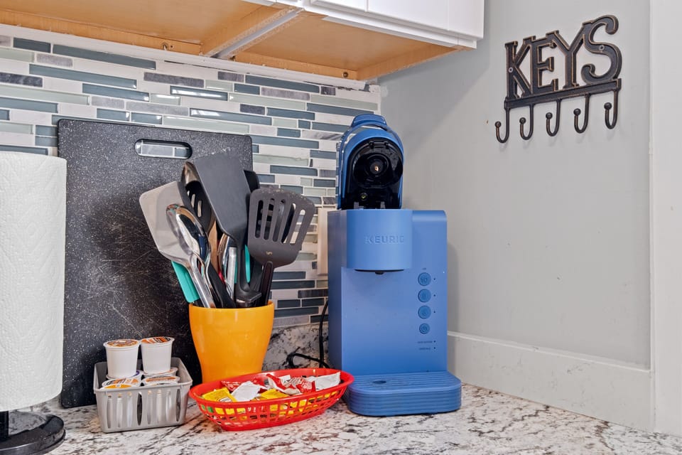 Kuerig coffee maker with pods and condiments in the kitchen.