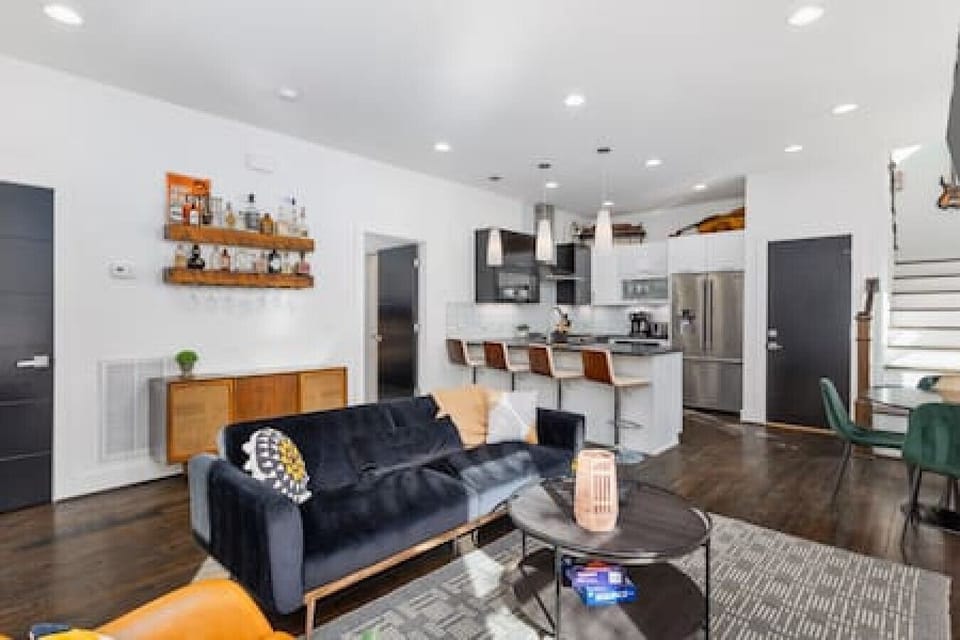 Open floor plan with a vintage record player, dining table, living room with a Smart TV, and seating for four at the kitchen counter.