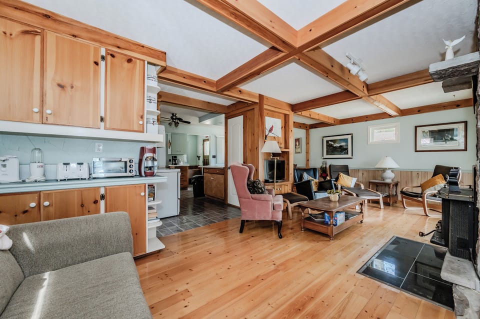 The heart of Beeshore, the living room features a warm fireplace, comfortable seating, and rustic wooden interiors. Perfect for gatherings, this space exudes a welcoming ambiance for relaxation and enjoyment.