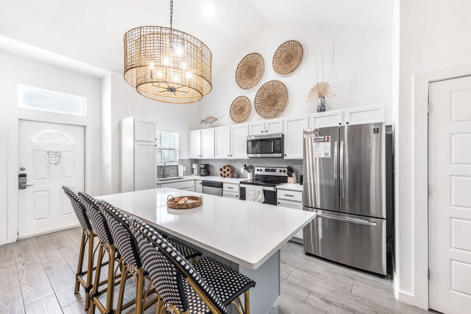 Your spacious kitchen awaits with white quartz countertops, stainless steel appliances, and a charming breakfast island perfect for morning coffee.