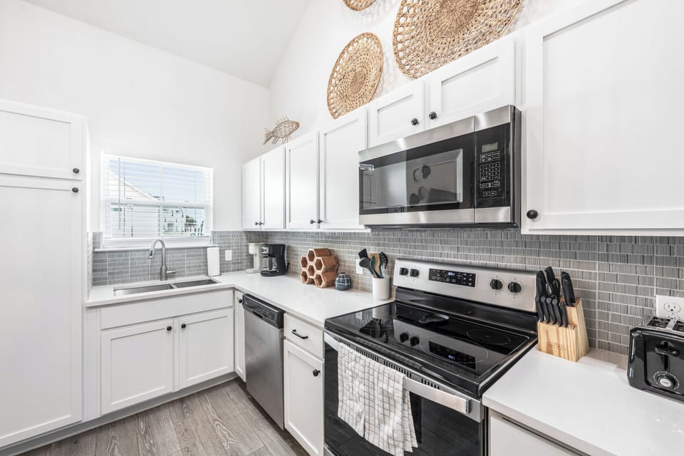 Cook your favorite meals in this bright, fully equipped kitchen with modern appliances, ample counter space, and charming woven basket décor.