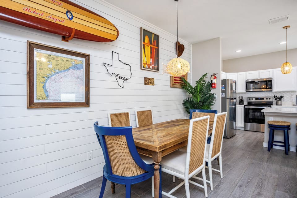 Gather around this coastal-inspired dining space where your meals become memorable moments beneath warm pendant lighting and charming nautical décor.