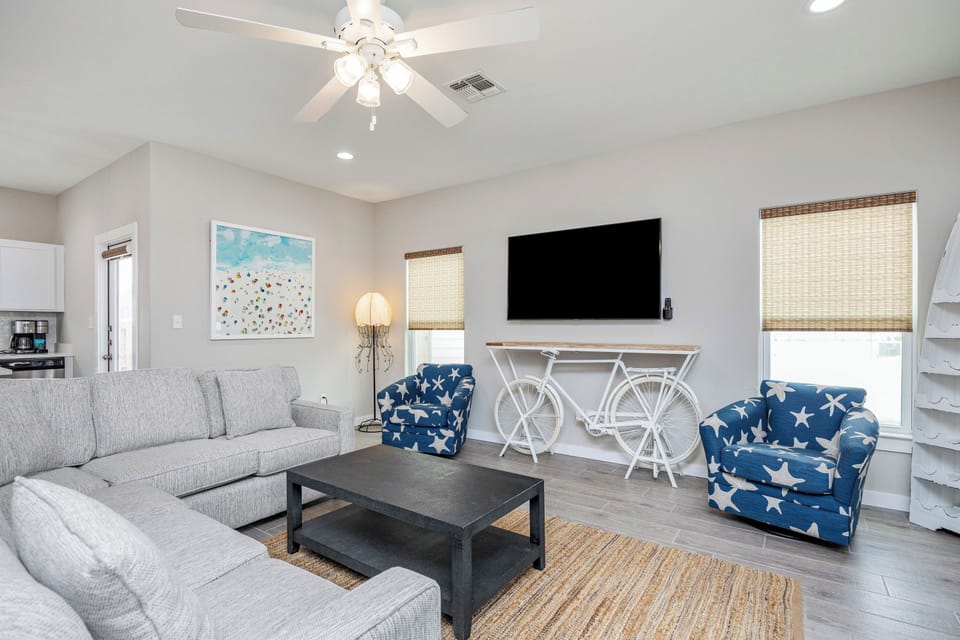 Relax in your bright living room with plush seating, unique bicycle console, and coastal charm.