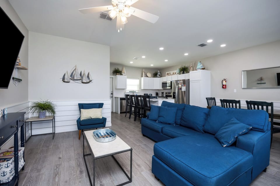 Unwind in your spacious living area featuring a plush blue sectional sofa and modern open kitchen, perfect for relaxing after exploring.