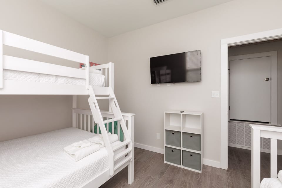 Your family will love this cheerful bunk room with crisp white linens, wall-mounted TV for movie nights, and organized storage.
