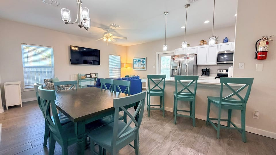 Your open-concept kitchen and dining space features coastal charm with turquoise chairs and modern amenities for memorable meals together.