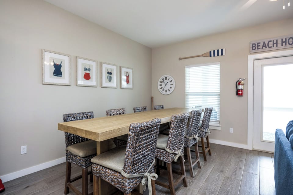 Your coastal dining space features vintage swimsuit prints and seating for eight, perfect for memorable group meals by the beach.