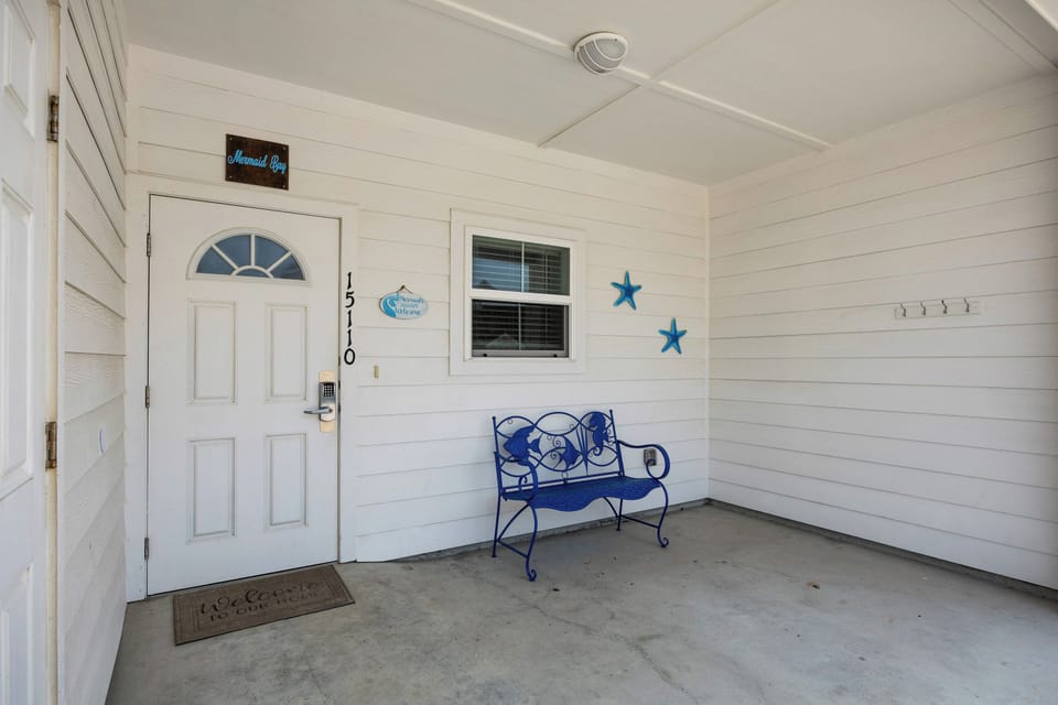 Your charming covered entryway welcomes you with coastal touches, featuring a cozy blue bench and nautical stars that set a relaxing seaside mood.
