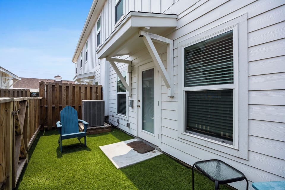 Relax in your private courtyard with artificial turf and a cozy blue chair, perfect for morning coffee or evening unwinding.
