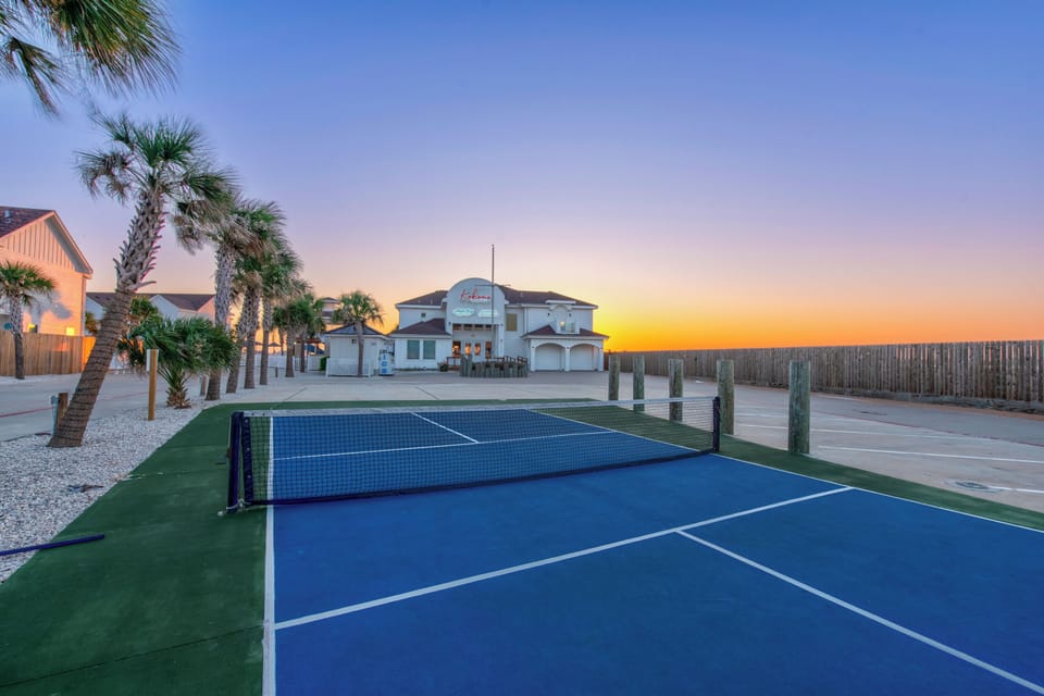 Challenge friends to Pickleball matches on the community court as golden sunsets paint the tropical sky behind swaying palms.