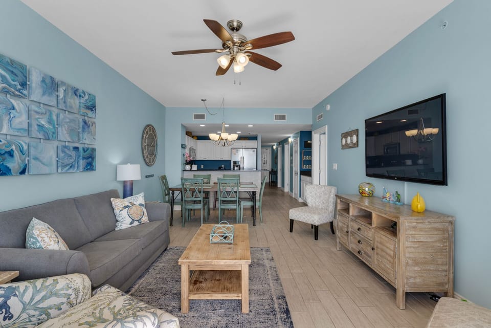 Living Room - Relax in luxury and comfort in this gorgeous living space featuring a large flat-screen TV, coastal decor, and a private balcony with breathtaking beach views.