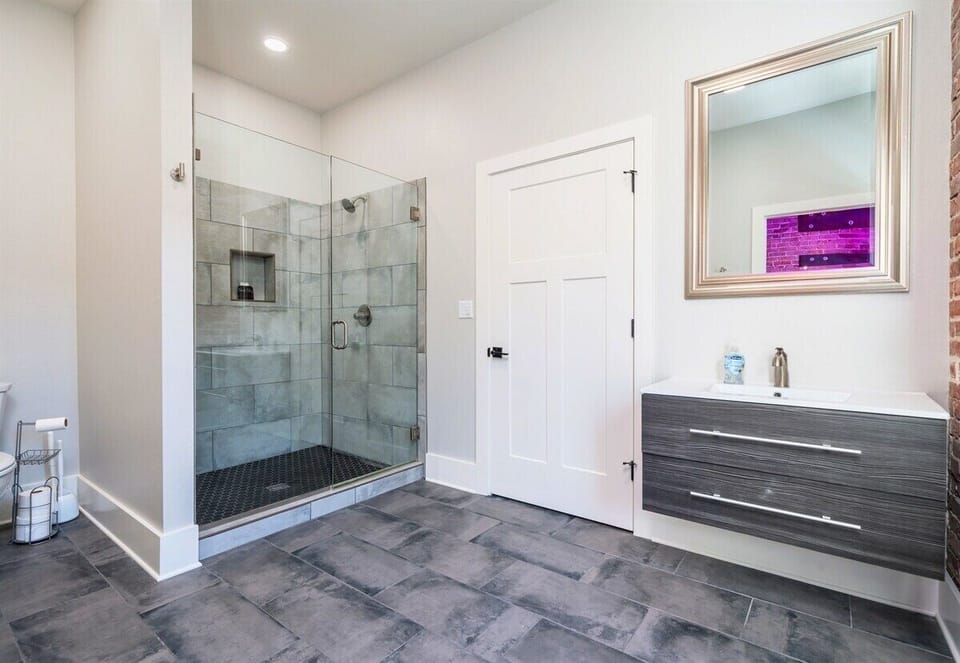 [Bathroom 1] The Bathroom Has a Walk in Shower and is Brightly Lit with a Floating Vanity Cabinet