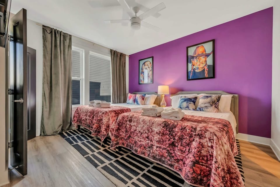 Two queen beds with purple accent wall give flexibility for couples, friends, or family sharing one bedroom comfortably