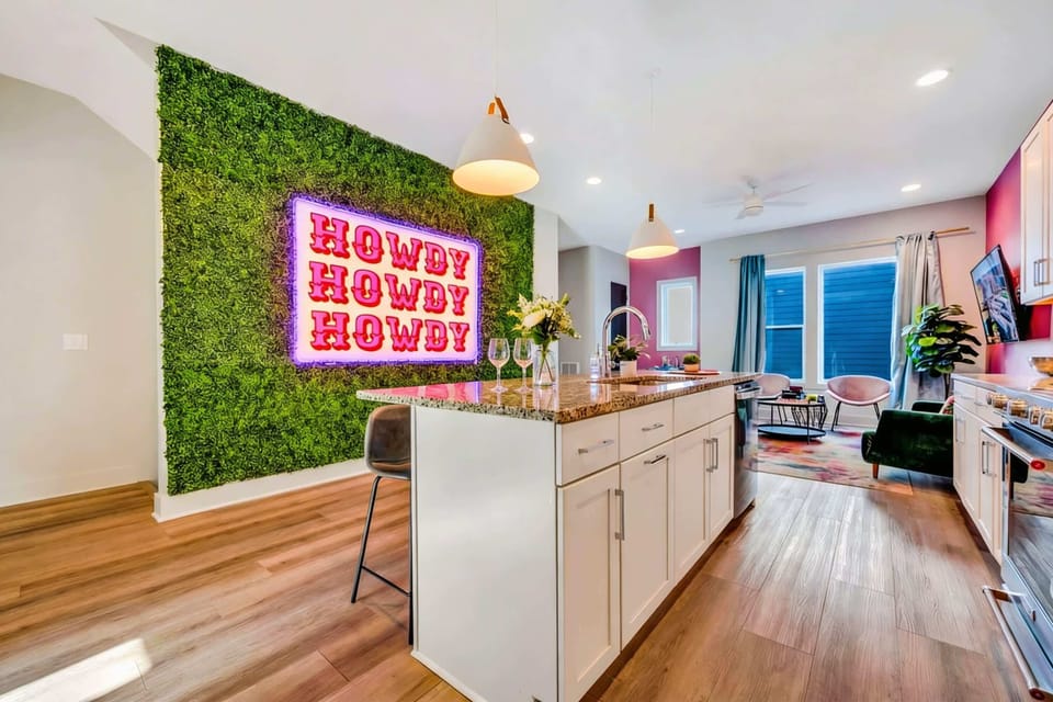 Open-plan kitchen and living room mean the cook stays part of the fun, with the neon sign and moss wall creating the backdrop for every meal and moment, book your stay with Misfit Homes