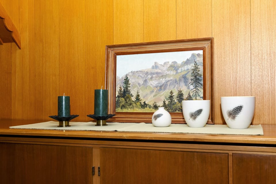 Decoration featuring a mountain scene, candles and vases on a wooden sideboard