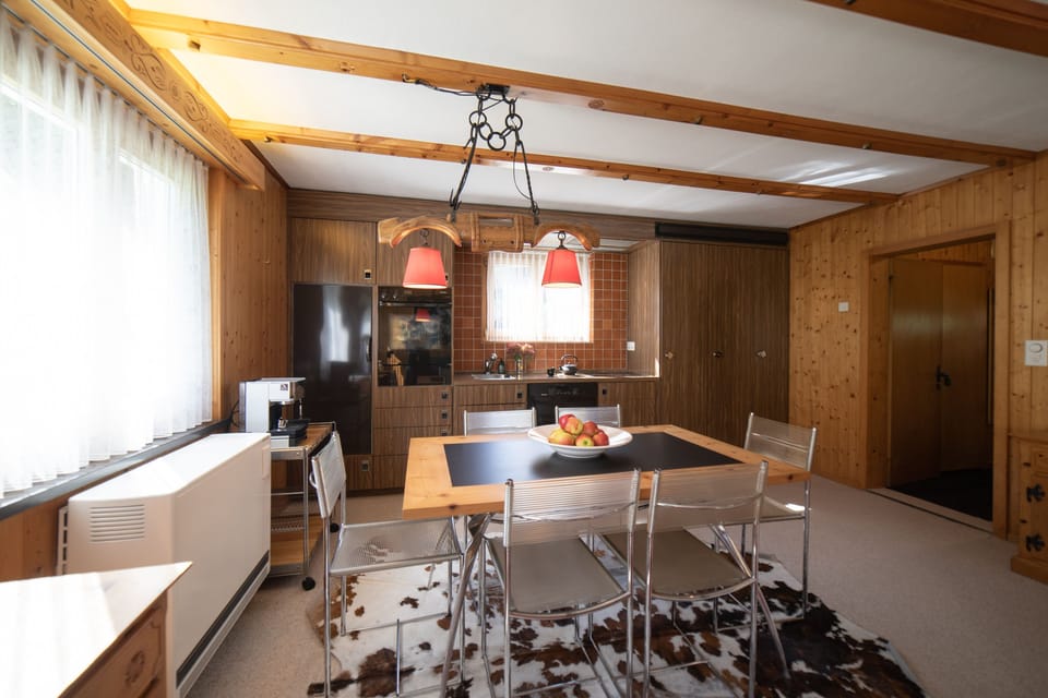 Dining area with wooden table and adjoining kitchen