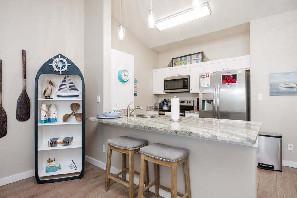 Your bright kitchen invites morning coffee sessions at the breakfast bar, while nautical touches add coastal charm to your culinary adventures.