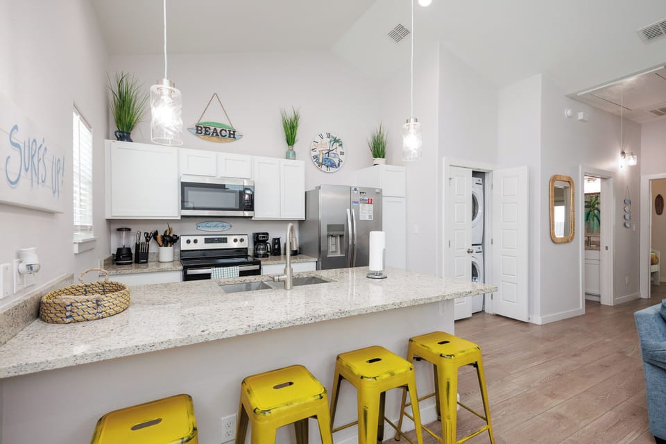 Your bright kitchen features granite counters, stainless appliances, and cheerful yellow bar stools perfect for morning coffee or casual meals together.