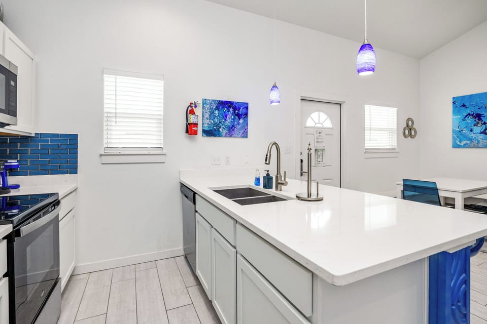 Your fully equipped kitchen awaits with crisp white countertops, blue coastal accents, and modern appliances ready for cooking.