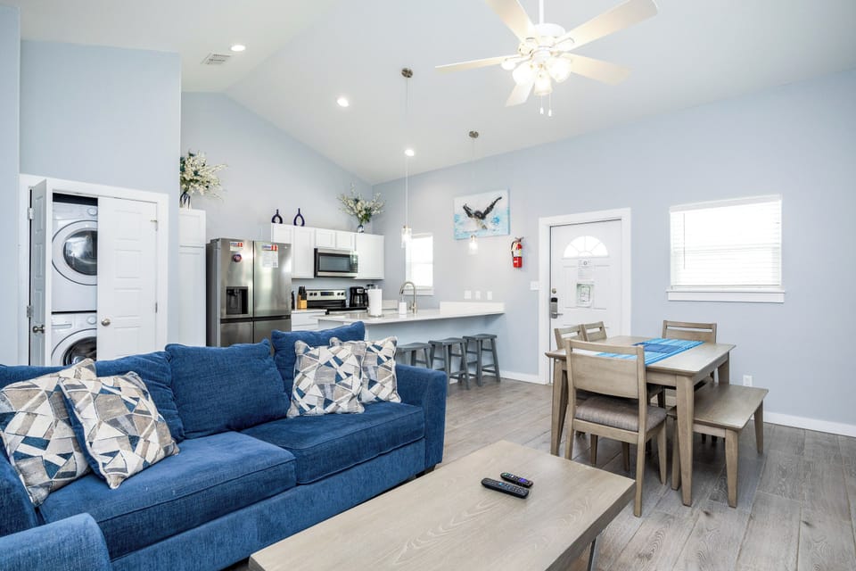 Relax in your bright, open living space with plush blue sofa, modern kitchen, and cozy dining area.
