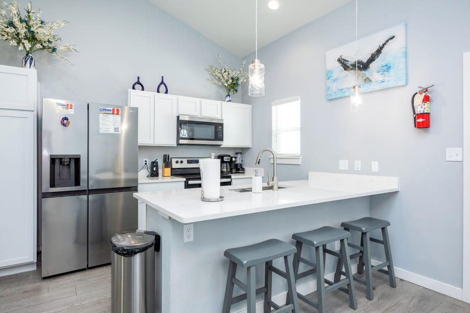 Gather with loved ones at your bright breakfast bar, featuring modern appliances and coastal-inspired décor for memorable meal prep moments.