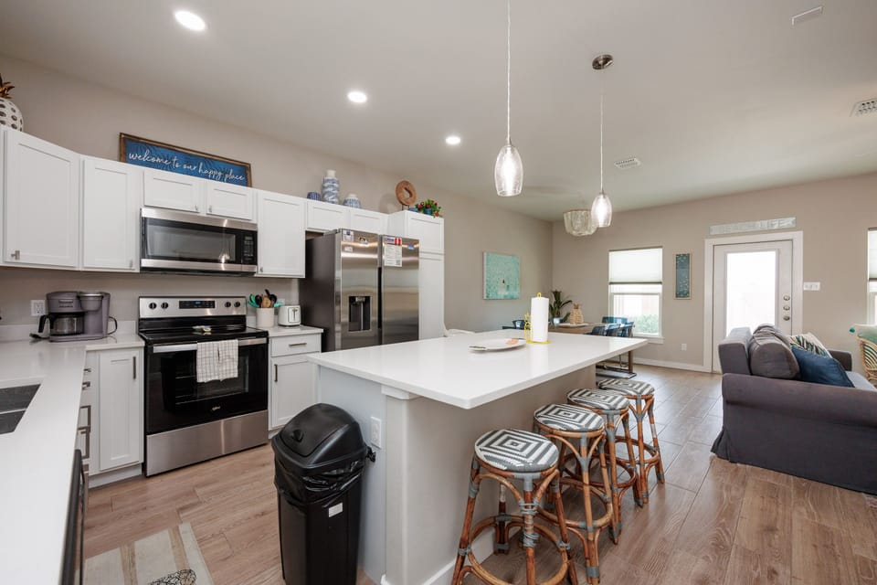 Your modern kitchen awaits with crisp white cabinets, stainless appliances, and a spacious island perfect for morning coffee or evening meals.