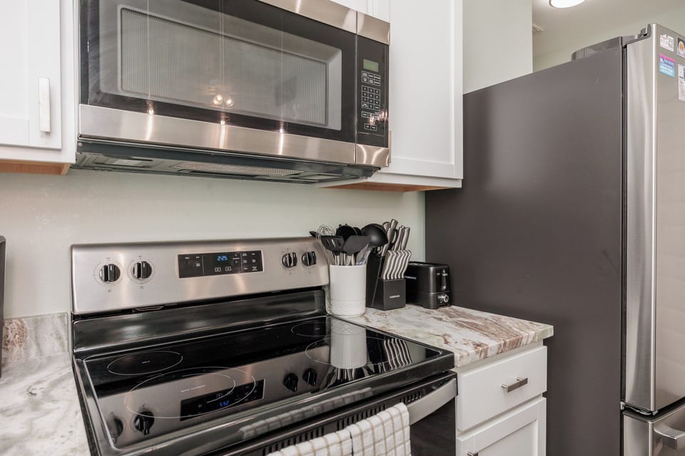Cook your favorite meals in this fully-equipped kitchen with modern stainless appliances and marble countertops.