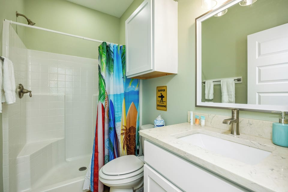 Refresh in your coastal-themed bathroom with a spacious shower, tropical curtain, and beach vibes throughout.