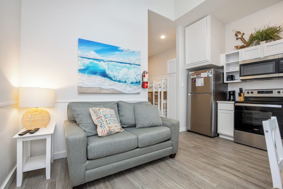 Your bright coastal retreat features a comfy sofa, full kitchen, and ocean artwork creating the perfect beachy vibe for your getaway.