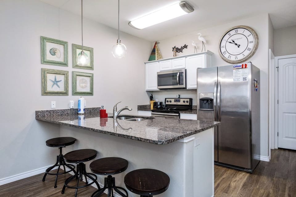Your fully equipped kitchen features granite countertops, stainless steel appliances, and a breakfast bar perfect for morning coffee or casual meals.