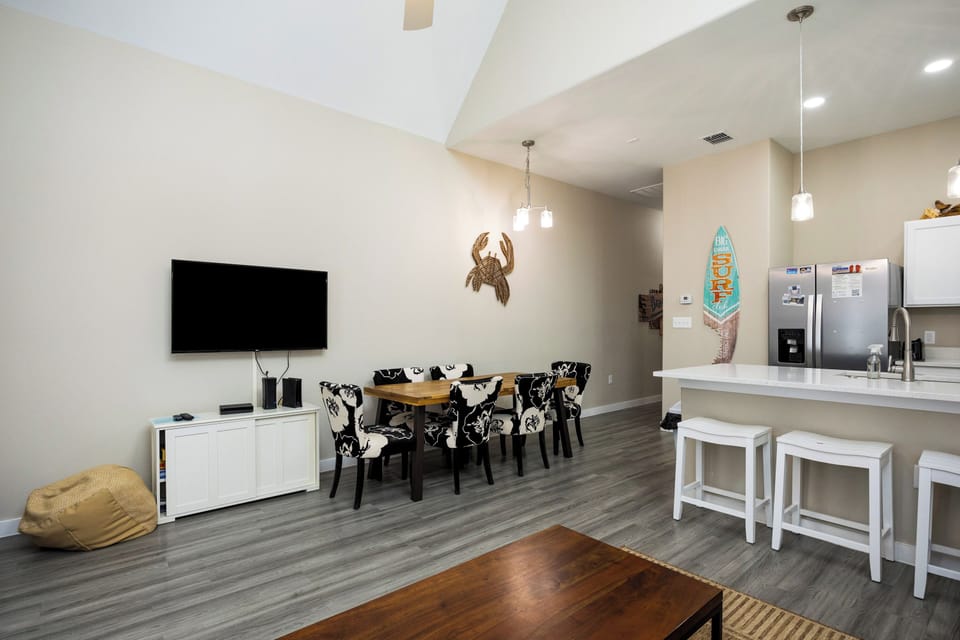 Relax in your stylish open-plan living space featuring modern kitchen, dining area, and entertainment center with coastal charm.