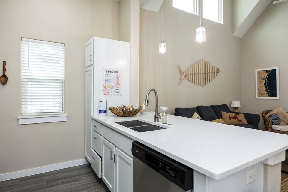 Your modern kitchen flows seamlessly into the living area, featuring sleek white countertops and contemporary finishes perfect for cooking memorable meals.