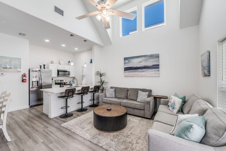 Relax in your spacious open-concept living area featuring vaulted ceilings, modern kitchen, and comfortable sectional seating perfect for gathering.