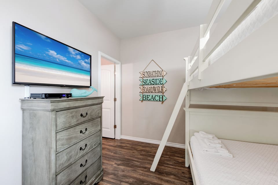 Your coastal bedroom with full-over-full bunk beds, beachside wall art, and flat-screen TV creates the perfect family retreat.