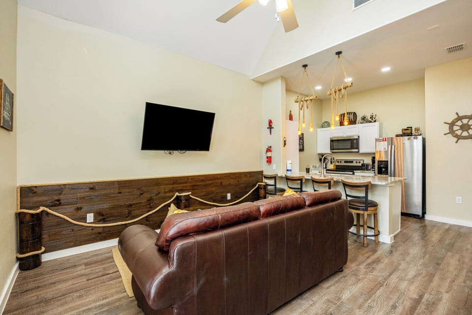 Your open-concept living space combines coastal charm with modern comfort, featuring leather seating and a fully equipped kitchen.