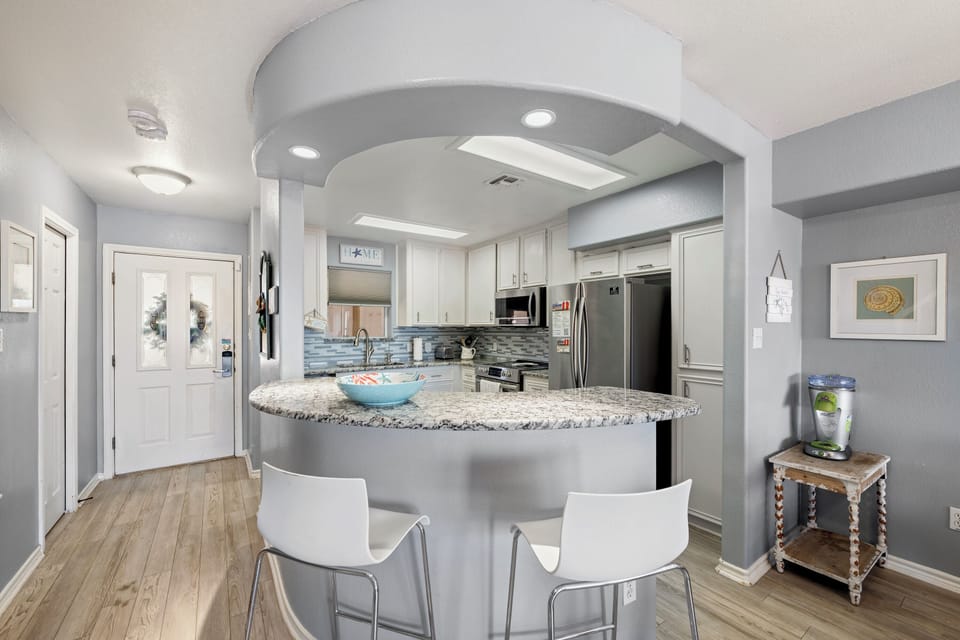Picture yourself whipping up a delicious meal in this open, modern kitchen with sleek granite countertops, stainless steel appliances, and a stylish curved island where you can enjoy breakfast or evening cocktails.