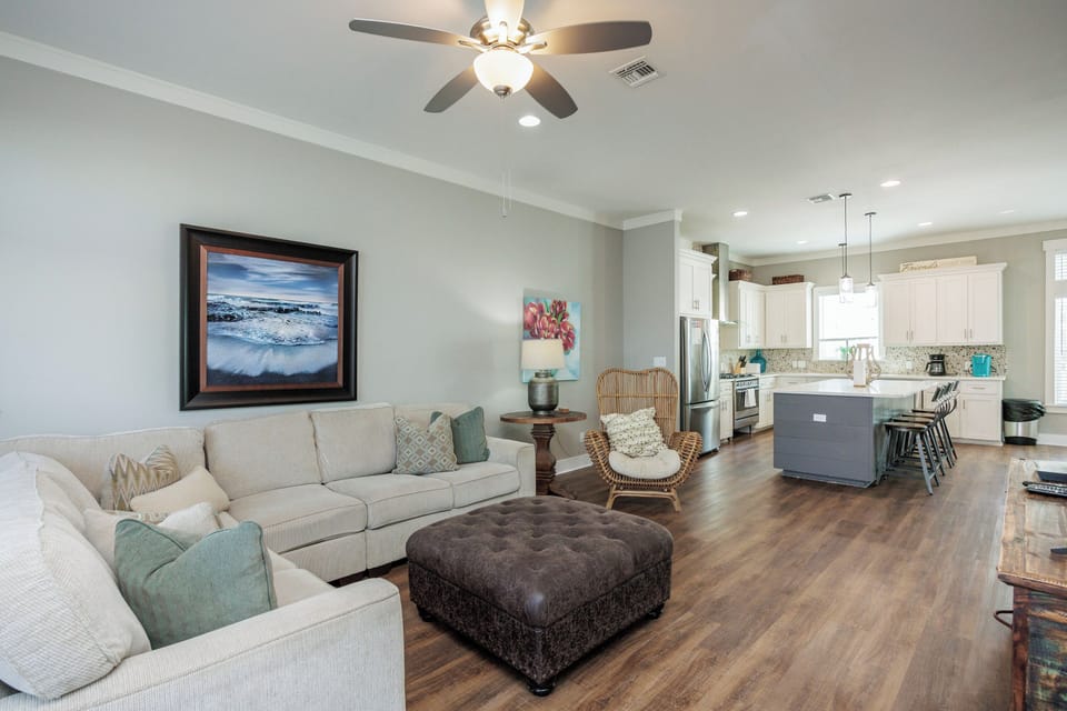 Settle into your spacious open-concept living area, where coastal artwork and plush seating create the perfect space to unwind after beach adventures.