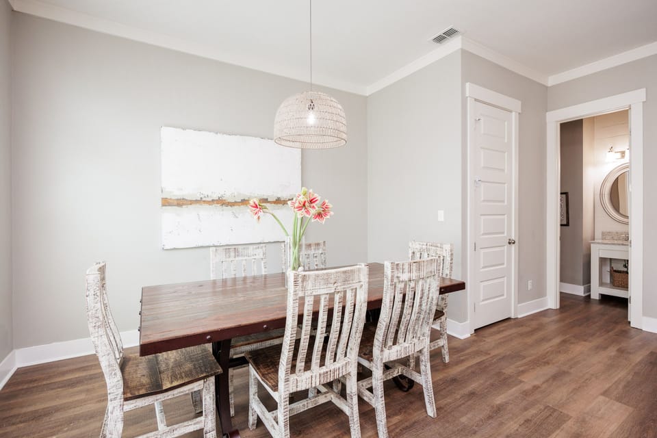 Gather around your elegant dining table for memorable meals beneath soft pendant lighting and contemporary coastal art.